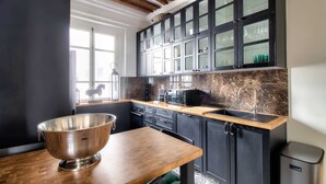 A modern kitchen with dark cabinetry, a wooden countertop, and a large metal mixing bowl.
