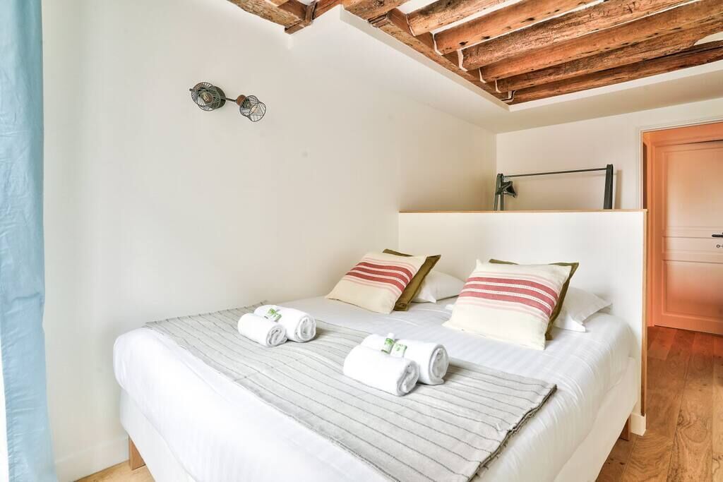 Un lit simple avec deux oreillers, une table de chevet et un plafond en bois.