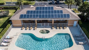Ein Gebäude mit Schwimmbad, Solaranlage auf dem Dach und Parkplatz.