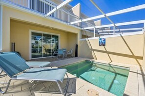 Uma área de piscina com espreguiçadeiras e uma porta de vidro que dá para um espaço interno.