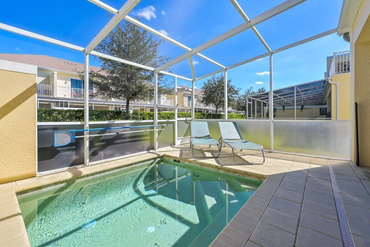 Une piscine extérieure couverte, dotée de chaises longues et entourée d’une structure en verre.