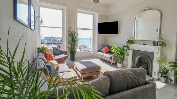 A living room with a sofa set, a fireplace, and a large window overlooking a cityscape. - The Esplanade (Weymouth)