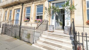 A historic building with a stone facade, multiple windows, and a black wrought iron fence. - The Esplanade (Weymouth)