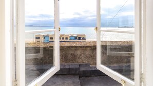 An open window with a view of a coastal area, including buildings and a body of water. - The Esplanade (Weymouth)