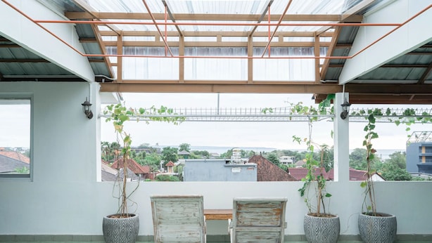 Une terrasse sur le toit, avec deux chaises en bois, deux plantes en pot et une vue sur le paysage urbain.