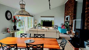 A modern living room with a wooden dining table, black chairs, a sofa, and a TV. - The Hillside Retreat, with amazing coastal and hinterland view. (Tamborine Mountain)