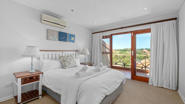 A bedroom with a bed, two nightstands, a window with curtains, and a view of greenery outside. - San Lameer Villa 10902 Private Pool  (Southbroom)