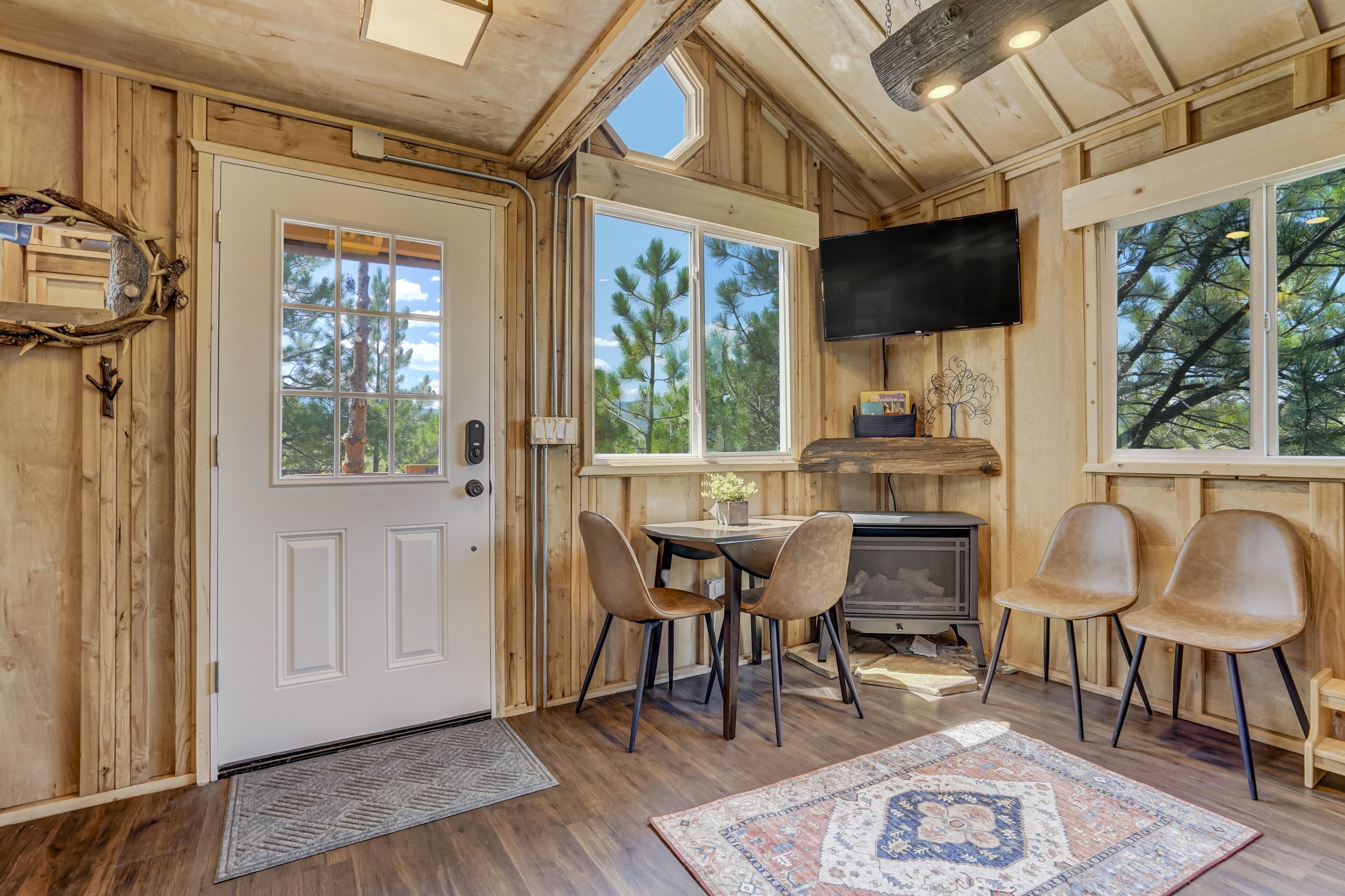 A wooden interior with a dining area, a fireplace, and large windows.