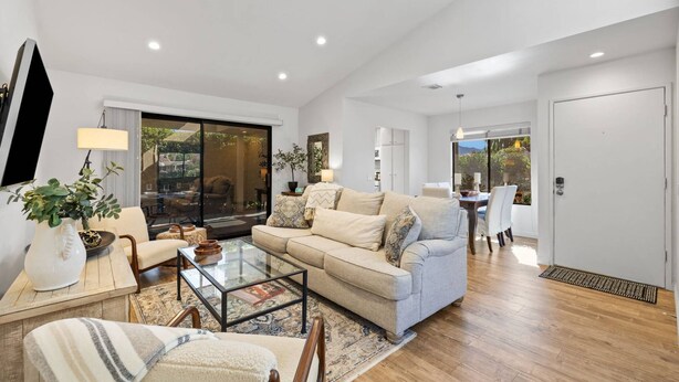 A modern living room with a sofa, coffee table, and chairs. There is a glass door leading to a balcony with plants. - Newly furnished Condo in Heart of Palm Desert! Pool, PickleBall! (Palm Desert)