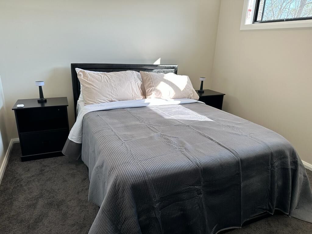 Ein Schlafzimmer mit einem Bett, zwei Nachttischen und einem Fenster.
