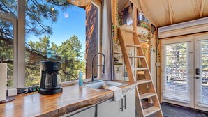 Une cuisine avec un plan de travail en bois, une machine à café, un évier et une échelle.