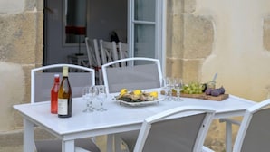 Une table à manger dressée avec une bouteille, des verres et un plateau de fruits.