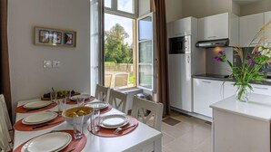 Une cuisine moderne avec des meubles blancs, un four à micro-ondes et un coin repas avec une table dressée pour quatre personnes.