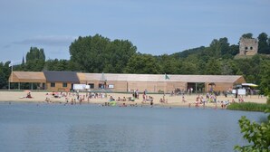 Ein Strand mit einem Holzgebäude, einem Spielplatz und einer Burg im Hintergrund.