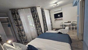 Ein Hotelzimmer mit Bett, Schreibtisch, Sessel und Fernseher.