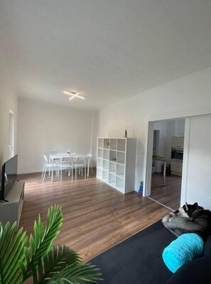 Relax in this open-plan living space with a dining area, sofa, and mounted TV.