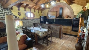 A rustic kitchen with a stone wall, wooden beams, and a tiled floor. - Casa Obis - Casa Rural con Jardín, Barbacoa y Unas Espectaculares Vistas (Muñeca)