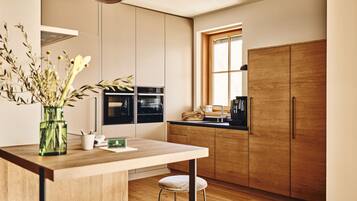 Una cocina moderna con armarios de madera, horno empotrado, cafetera y ventana que proporciona luz natural.