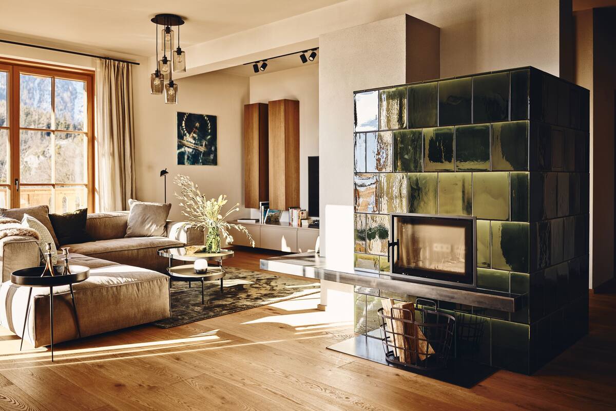 A modern living room with a large fireplace, wooden flooring, and a sofa with cushions.