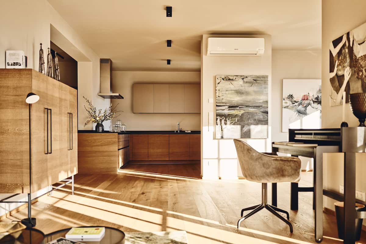 A modern kitchen with wooden cabinets, a central island, and a dining area with a chair and table.
