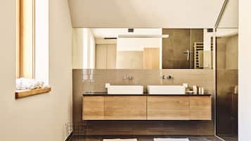 A modern bathroom with a large mirror, two sinks, and a wooden vanity.