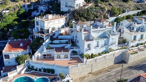 An aerial view of a residential area with white buildings, a swimming pool, and a stone wall. - Beautiful apartment in villa for 4 guests with pool, WIFI, TV and terrace (Roses)