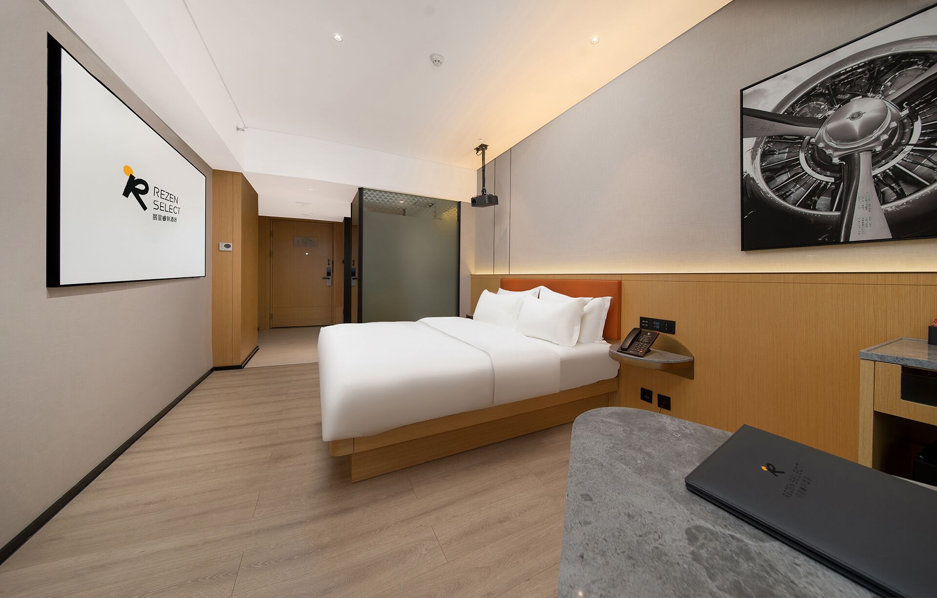 Ett modernt hotellrum med en säng, ett skrivbord och ett stort konstverk på väggen.