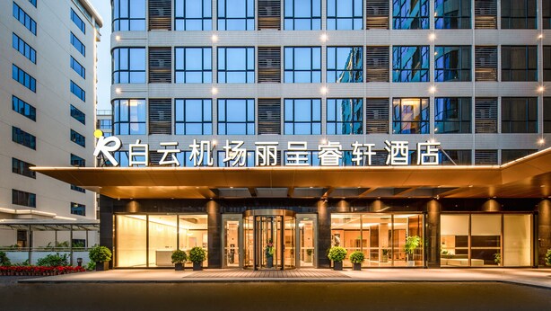 A hotel entrance with a modern design, featuring a glass facade and a welcoming entrance with a revolving door. - Guangzhou Baiyun Airport Rezen Select Hotel (Guangzhou)