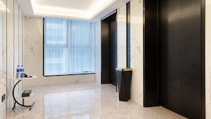 A modern hotel lobby with a marble floor, a glass table with water bottles, and two black elevators. - Guangzhou Baiyun Airport Rezen Select Hotel (Guangzhou)