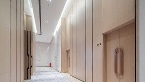 A modern hallway with wooden paneling, a patterned carpet, and a ceiling with recessed lighting. - Guangzhou Baiyun Airport Rezen Select Hotel (Guangzhou)