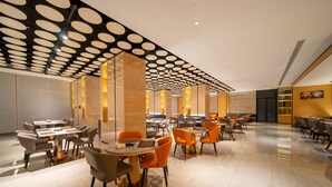 A modern dining area with round tables and chairs, a patterned ceiling, and a warm color scheme. - Guangzhou Baiyun Airport Rezen Select Hotel (Guangzhou)
