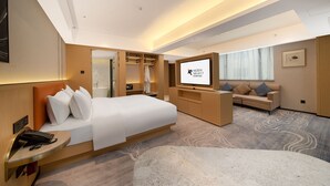 A modern hotel room with a large bed, a TV, a sofa, and a desk with a phone. - Guangzhou Baiyun Airport Rezen Select Hotel (Guangzhou)