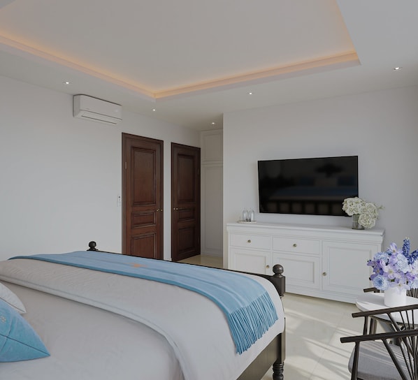 A bedroom with a bed, a TV, a dresser, and a vase of flowers.