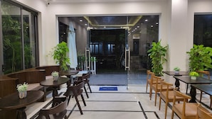 Un comedor moderno con mesas y sillas, plantas en macetas y una vista despejada del exterior.