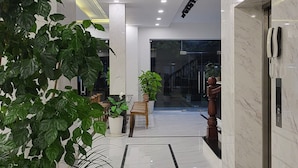 Un vestíbulo moderno con piso de mármol, plantas en macetas y una mesa de recepción.