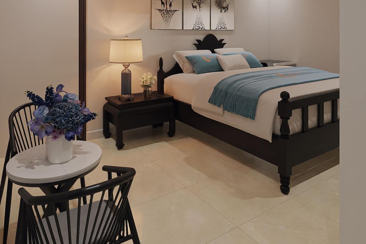 A bedroom with a bed, bedside tables, a chair, a lamp, and wall art.
