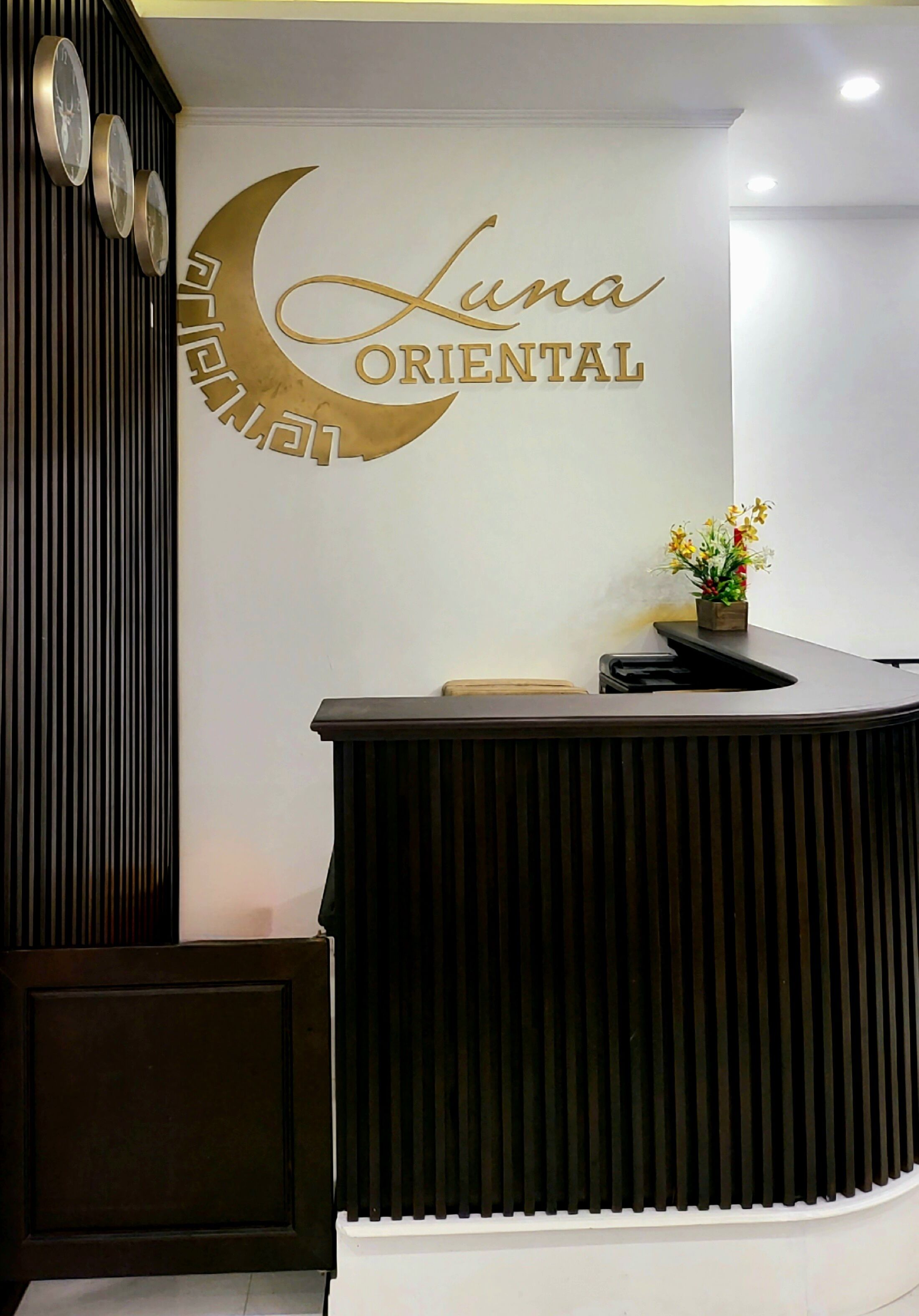 A reception desk with a logo that reads "Luna Oriental" and a decorative wall with a crescent moon design.