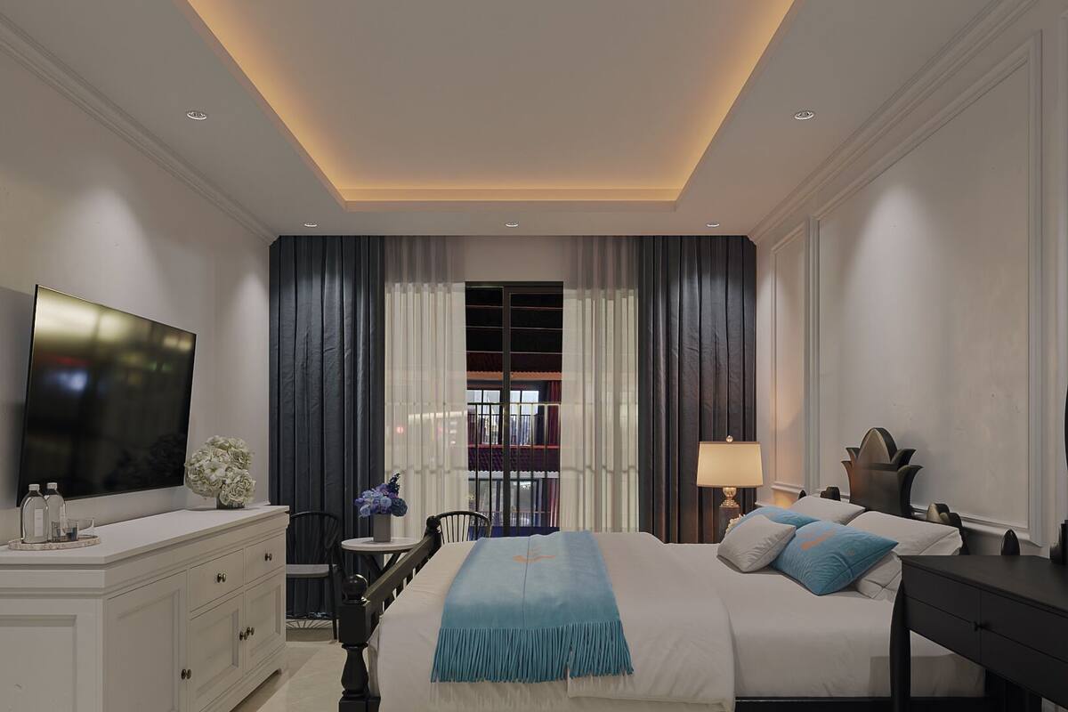 A modern hotel room with a large bed, a TV, a desk, and a view of the outside.
