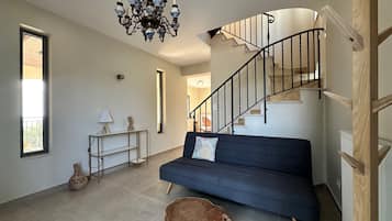 A modern interior with a staircase, a sofa, a chandelier, and a vase.