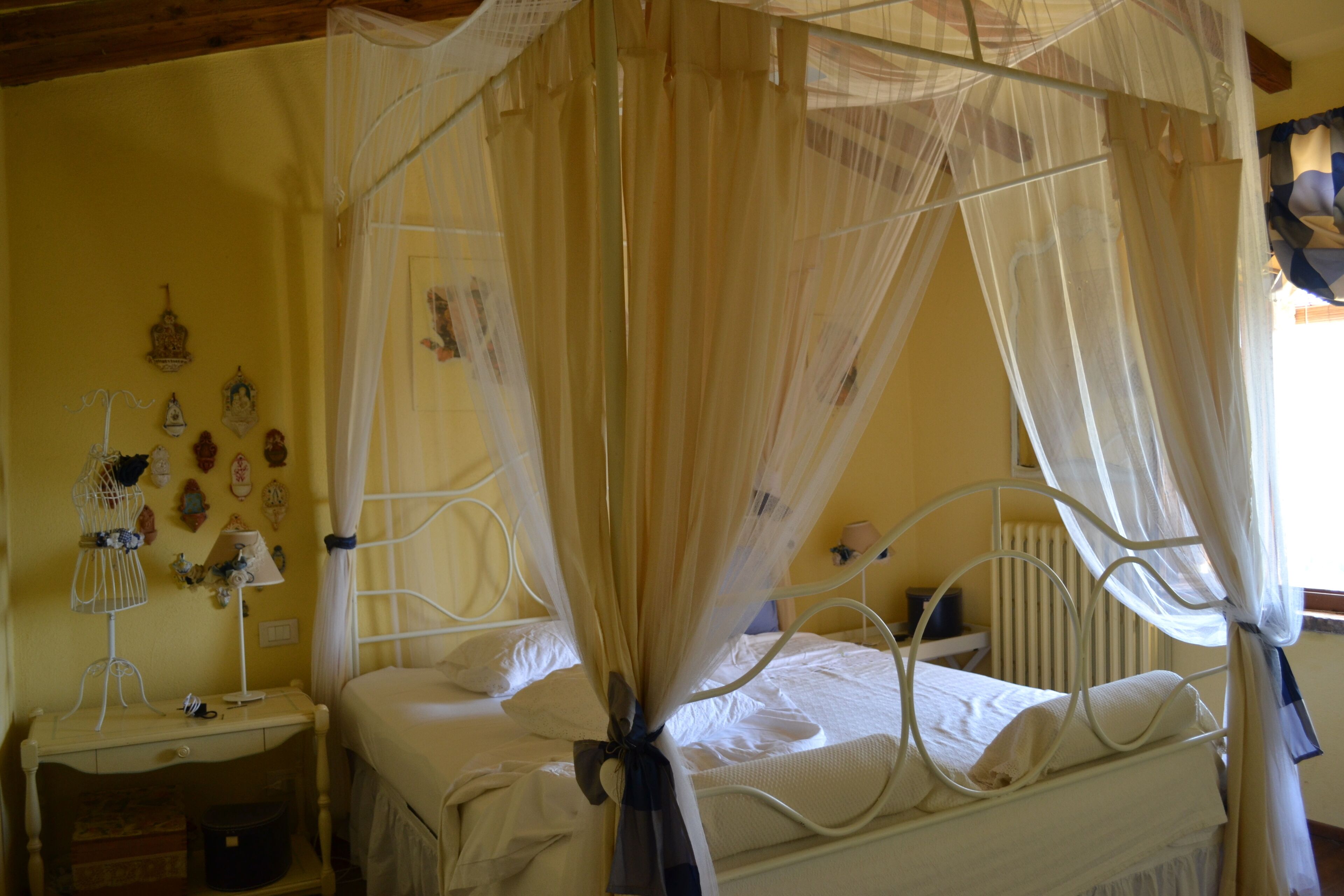 Un lit à baldaquin, une table de chevet, une lampe et des éléments de décoration murale.
