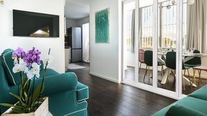 Un salon moderne avec des canapés de couleur turquoise, un téléviseur à écran plat et un coin repas comprenant une table et des chaises.