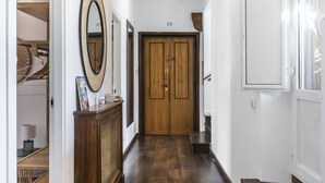 Un couloir avec un plancher en bois, une porte en bois et un miroir accroché au mur.