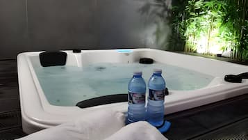 Un jacuzzi con dos botellas de agua, una toalla y una planta al fondo.