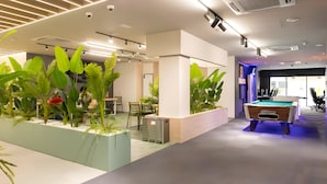 Un espacio interior moderno con mesa de billar, zona de estar y plantas de interior.
