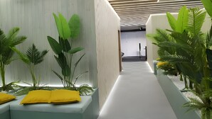 Un pasillo moderno con iluminación empotrada, plantas verdes y un suelo estampado.