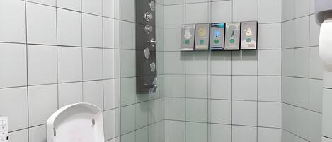 A modern bathroom with a white toilet, a glass shower enclosure, and a hand dryer.