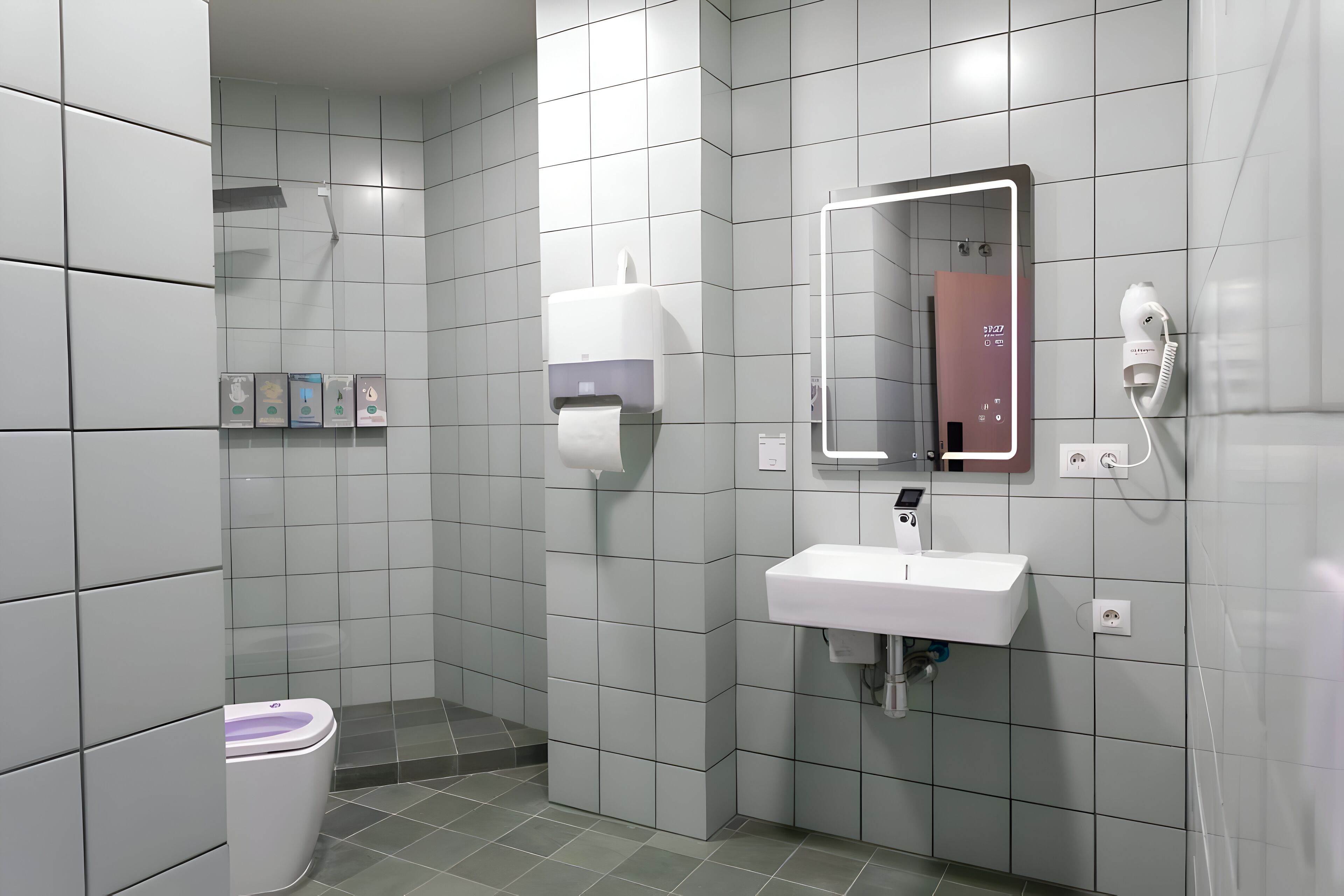 Une salle de bain moderne équipée de toilettes, d’un lavabo et d’un sèche-mains.