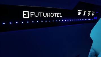 Un cartell futurista d'hotel amb el nom FUTUROTEL, i icones que representen serveis com ara un lavabo, un llit i un telèfon mòbil.