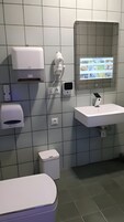 Un baño moderno con inodoro, lavabo y secador de manos.