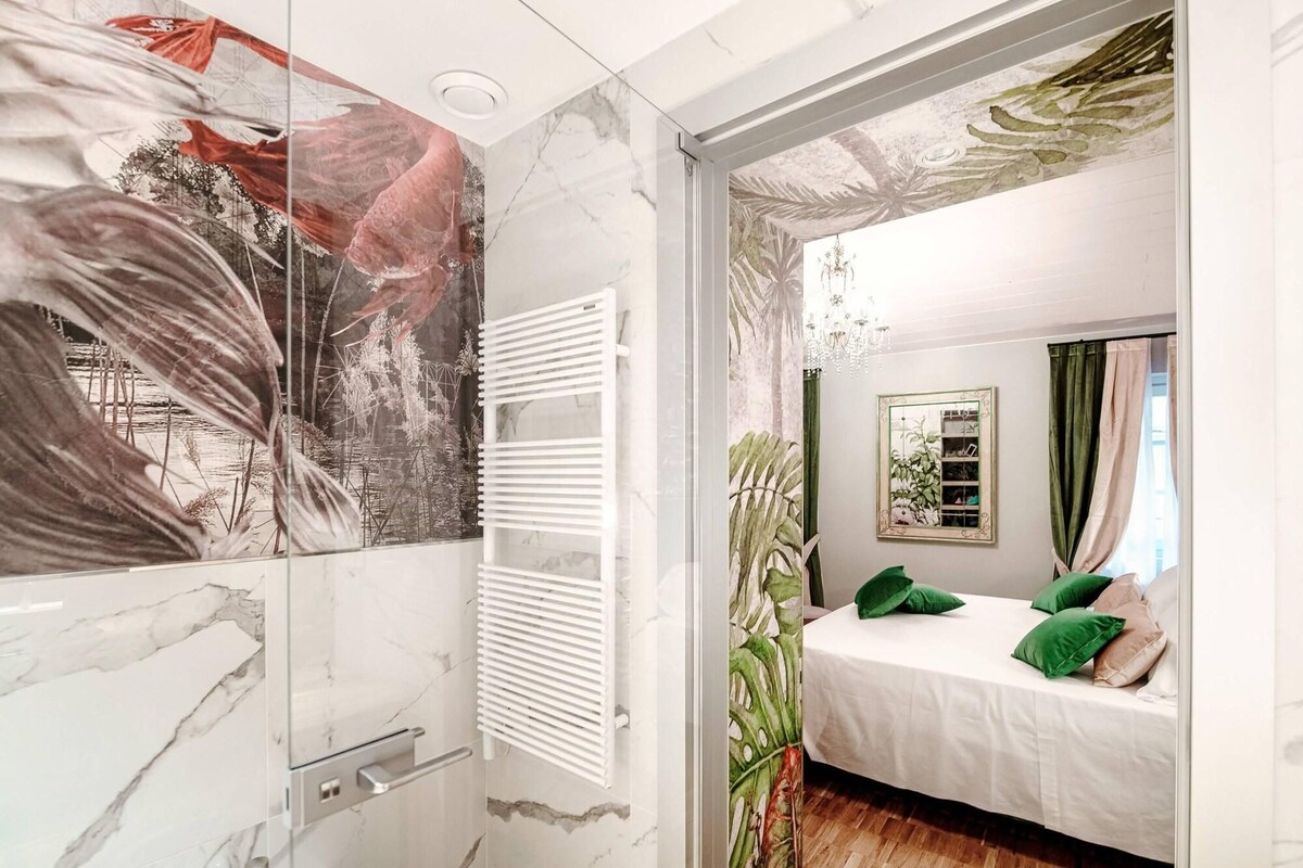 A bedroom with a bed, green pillows, a mirror, and a window with curtains.